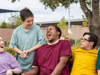 Group of teenagers with disabilities laughing together.