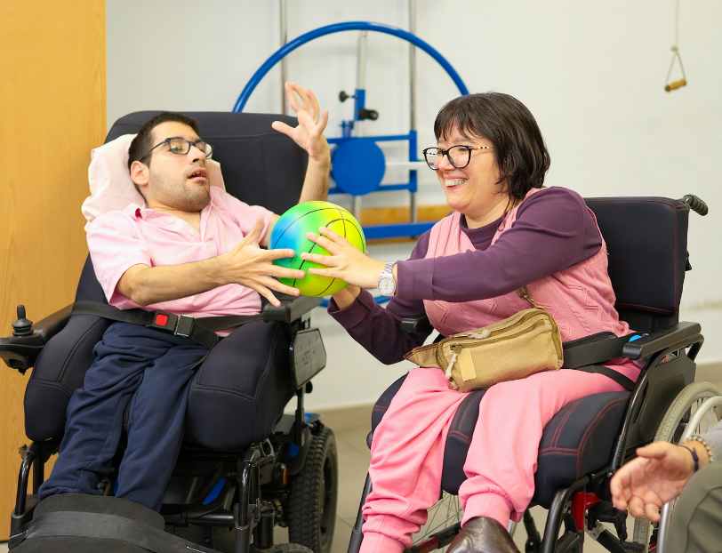 two wheelchair users passing a ball in a day centre